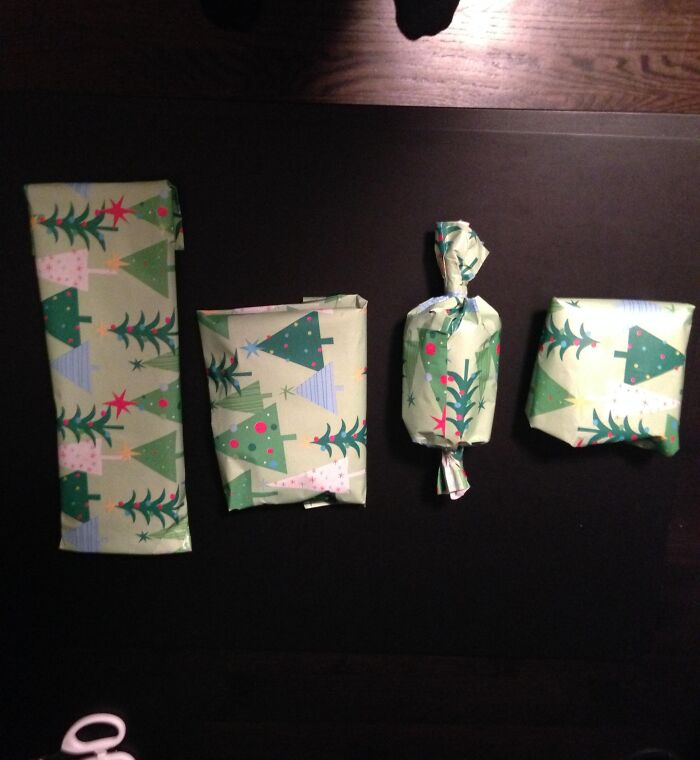Four Christmas gifts wrapped with funny gift wrap featuring various decorated green Christmas trees on light green paper.