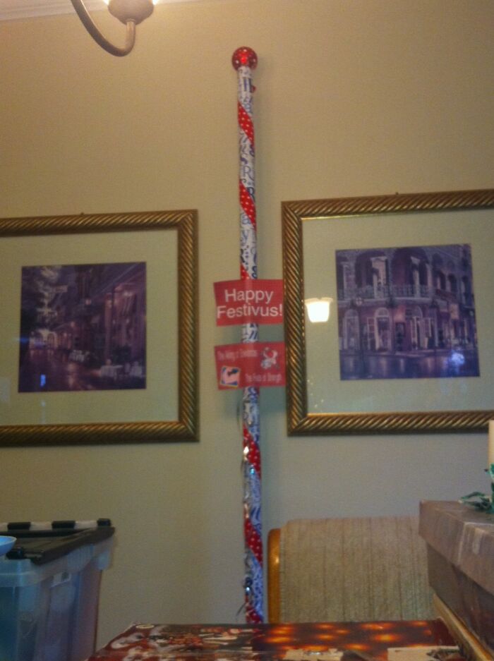 Festively wrapped pole with "Happy Festivus" sign in a living room, showcasing funny gift wrap ideas for Christmas mischief.