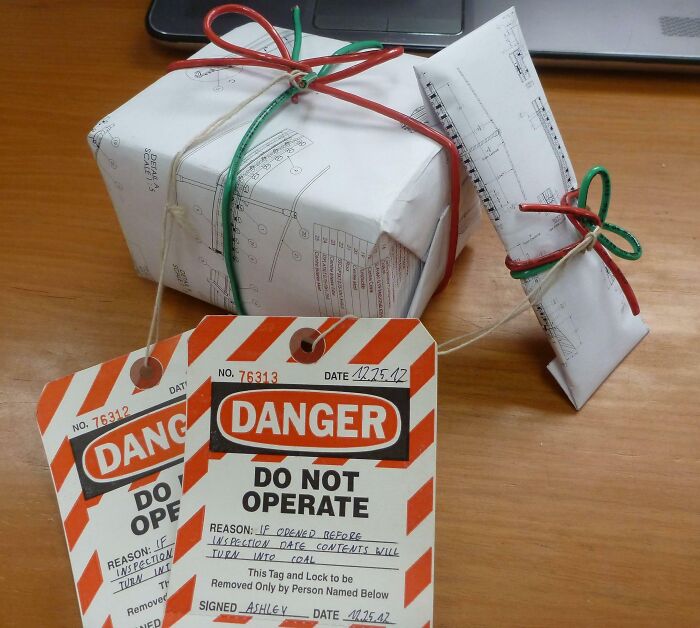 Gift wrapped boxes with hazard-style tags and red and green string, showcasing funny gift wraps for Christmas mischief.