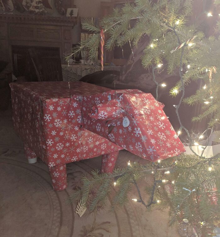 Festive funny gift wrap shaped like an animal under a Christmas tree with lights, inspiring holiday mischief.