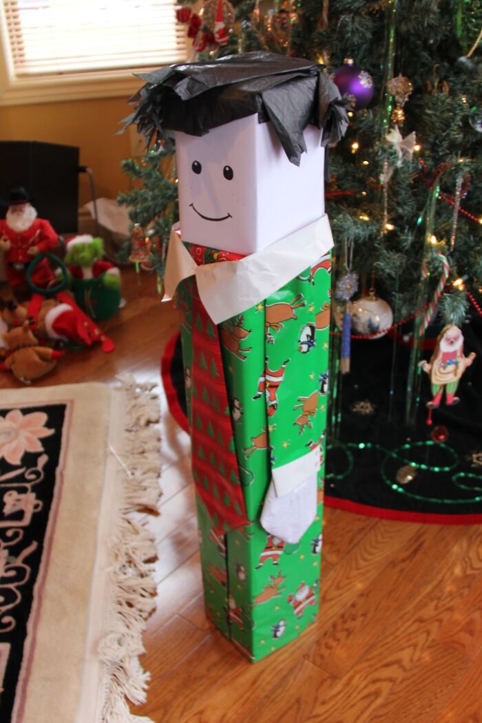Tall gift with creative wrapping made to look like a person, featuring funny gift wrap ideas for Christmas mischief.