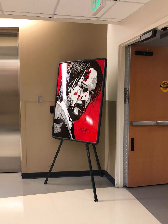 Illustration of a serious man with blood splatters on his face displayed on a stand in an office hallway, job photos.