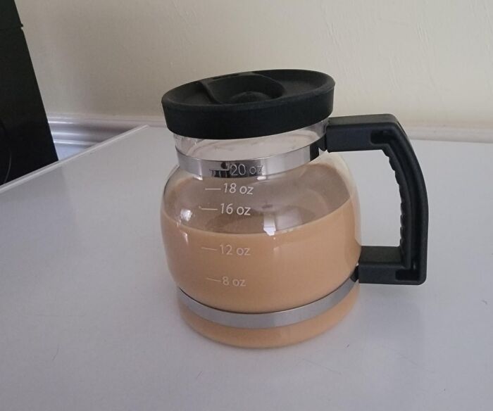 Clear glass coffee pot filled with beige liquid on white surface, perfect for unique and never-before-seen gifts.