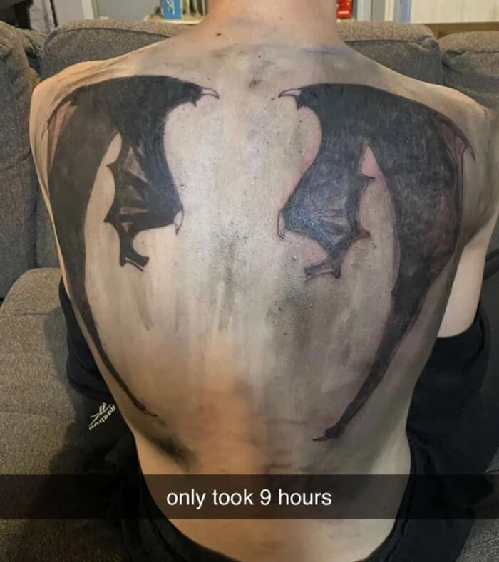 Back tattoo of black wings with a caption highlighting a worst tattoo that took nine hours, featured in an online group.