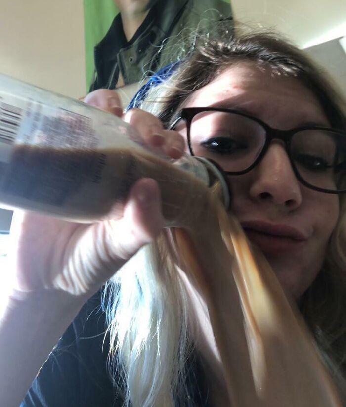 Woman wearing glasses pouring drink on her face, a funny and weird pic taken at the perfect time.