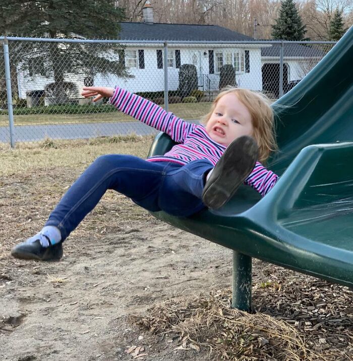 Child caught in a funny and interesting moment sliding awkwardly off a playground slide in a perfect timed pic.