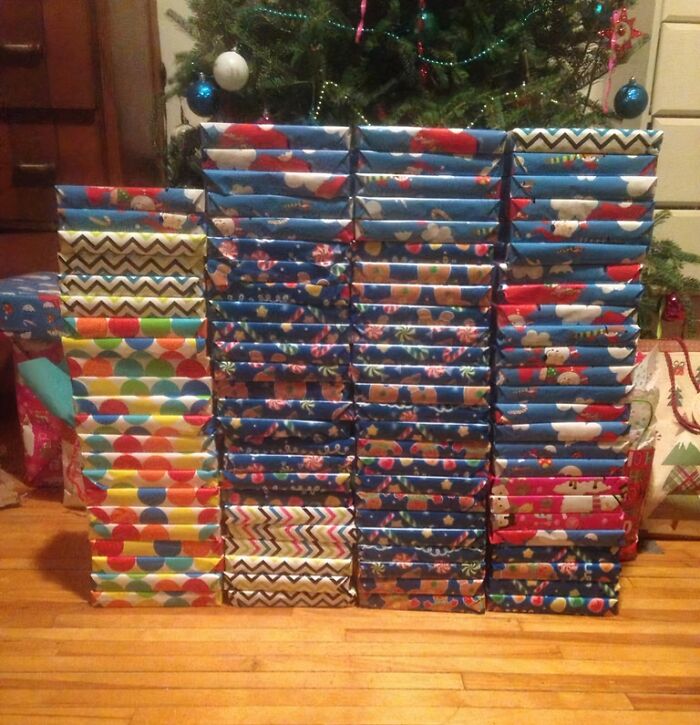 Stack of neatly wrapped Christmas presents with colorful and festive funny gift wraps under a decorated tree.