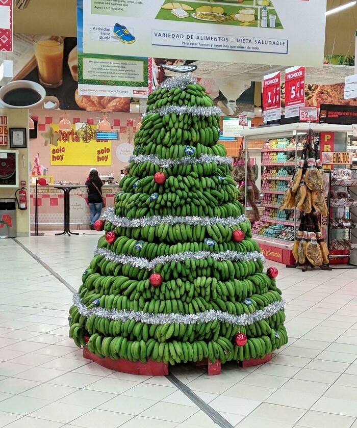Creative workplace Christmas decoration featuring a large tree made entirely of green bananas with festive ornaments.