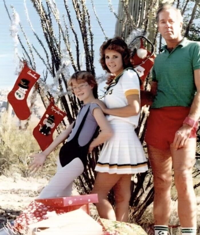 Family posing in awkward Christmas outfits outdoors with stockings and wrapped presents, capturing hilarious family Christmas photo moments.