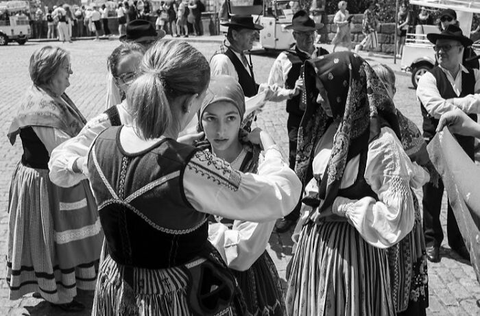 Women and men in traditional clothing sharing street moments that capture the marvels of daily life in a lively public setting.