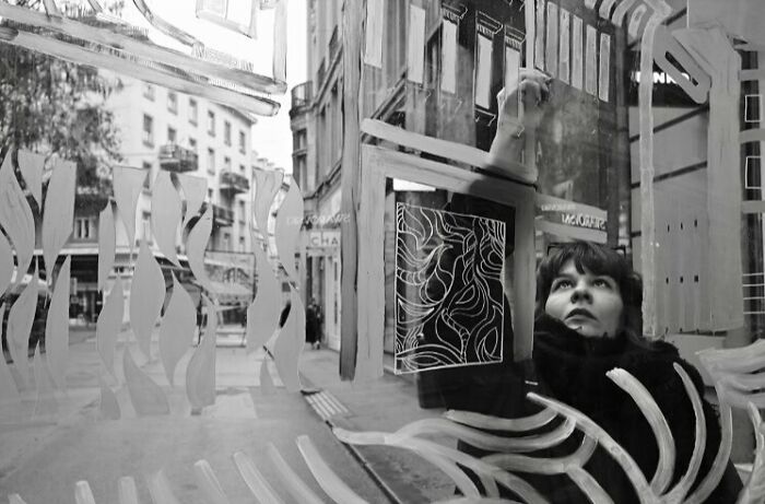 Person painting abstract patterns on a window, capturing street moments that feel like magic in daily life.