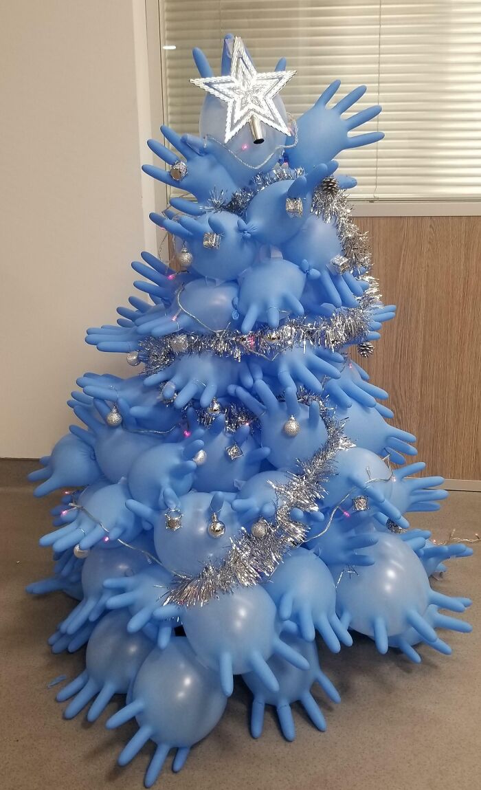 Creative workplace Christmas decoration made from blue inflated gloves arranged as a unique holiday tree with silver tinsel and ornaments.
