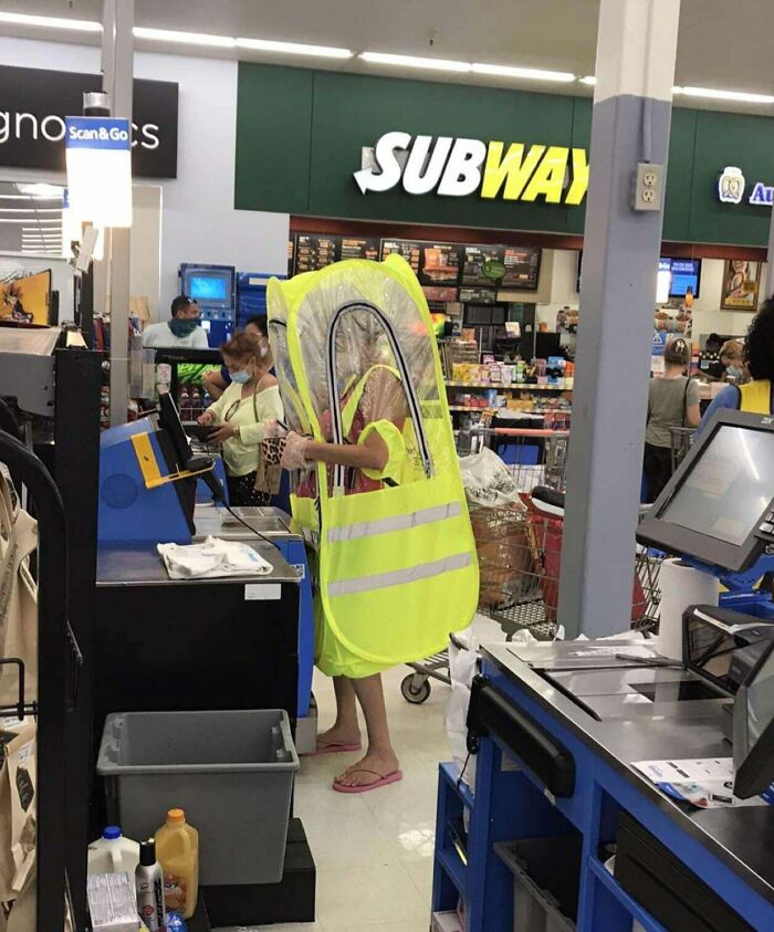 Person in a bright yellow protective suit using a self-checkout at Walmart, showcasing unusual scenes inside stores.