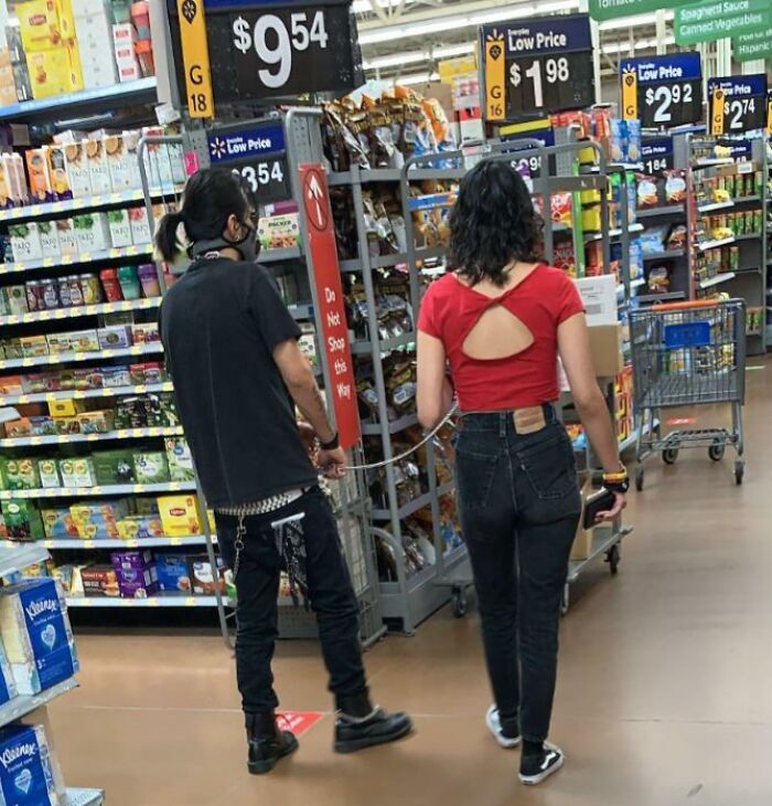 Two shoppers connected by a chain walking inside Walmart, showcasing unusual moments in Walmart stores.