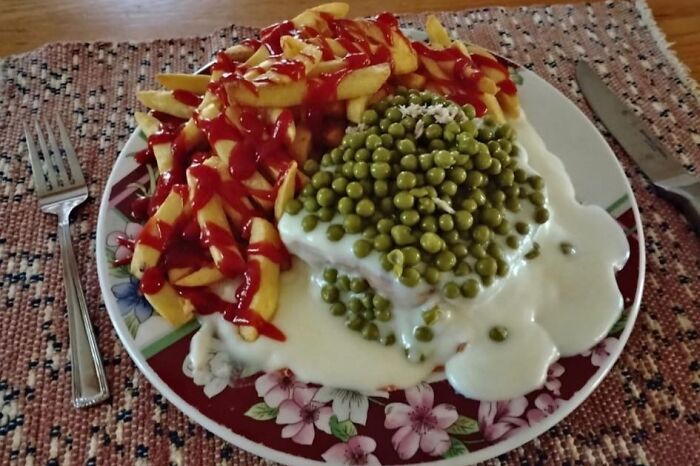 Plate of fries topped with ketchup and peas covered in white sauce, an unusual food pic deserving to be shamed online.