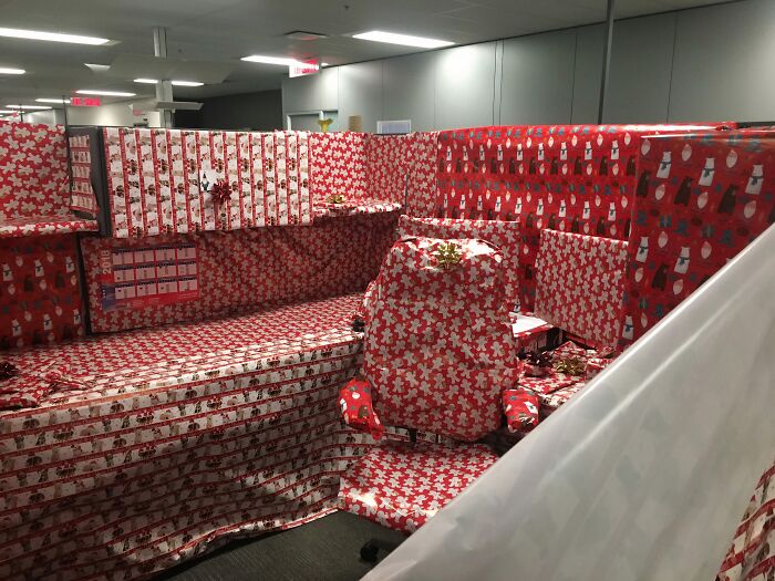 Office cubicle covered entirely with creative Christmas decorations wrapping paper, showcasing festive workplace creativity.