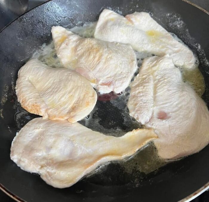 Partially cooked chicken breasts in a pan with uneven cooking and raw spots, a food pic that deserves to be shamed online.