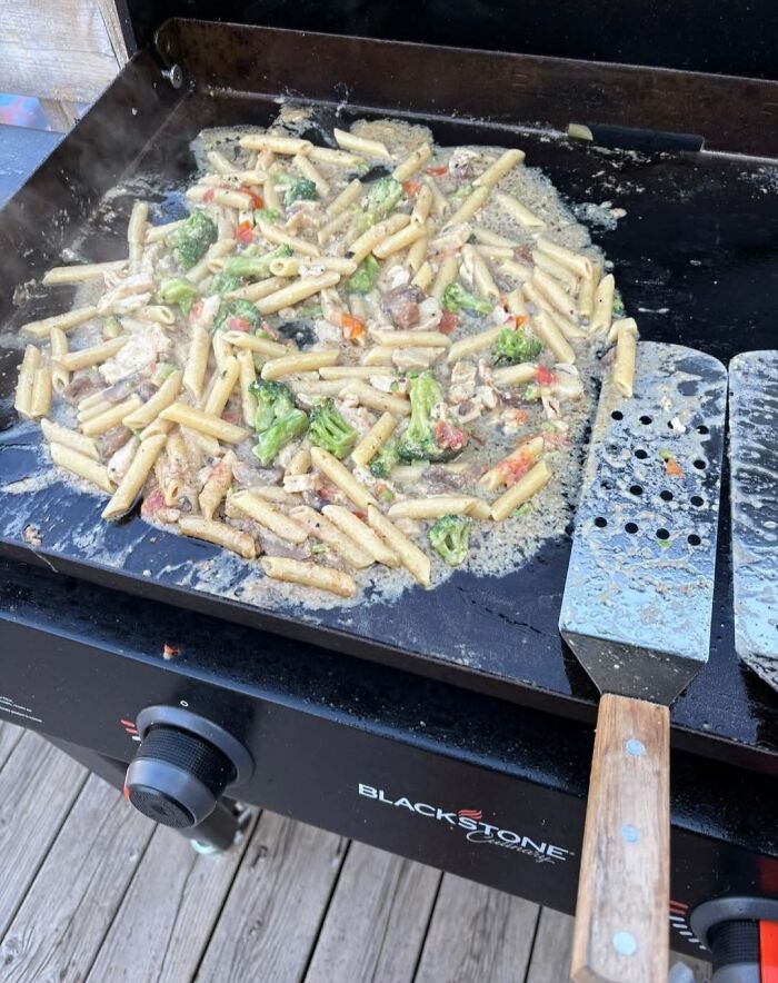 Pasta with mixed vegetables cooking unevenly on a Blackstone griddle, an example of food pics that deserve to be shamed online