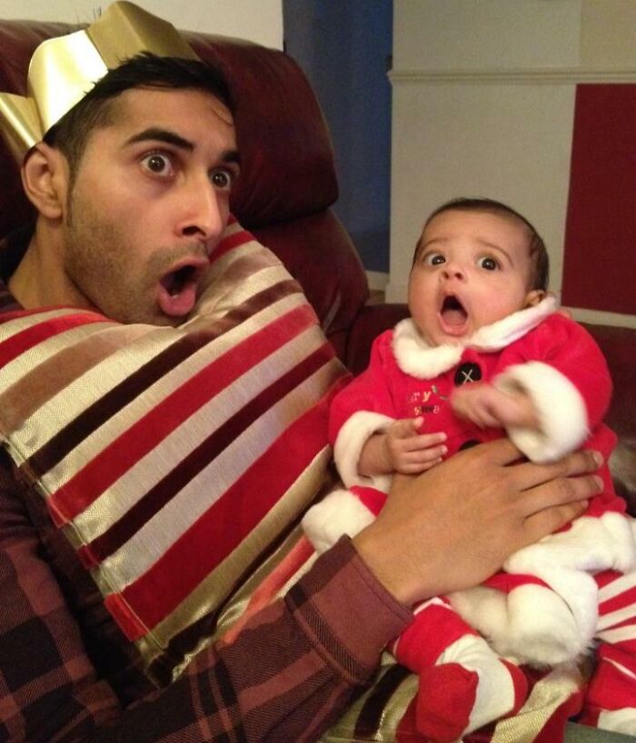 Man and baby wearing festive clothes making surprised faces in a hilariously awkward family Christmas photo.