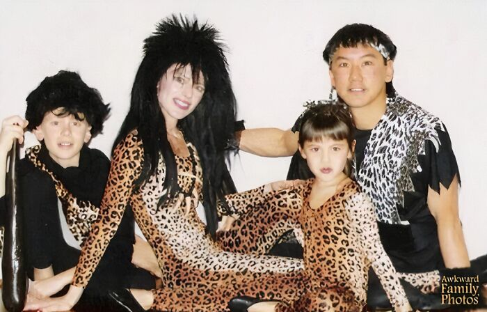 Family dressed in leopard print costumes posing awkwardly in a hilariously awkward family Christmas photo moment.