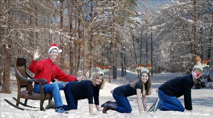 Family dressed in Christmas-themed outfits posing awkwardly in the snow with Santa hat and reindeer antlers.