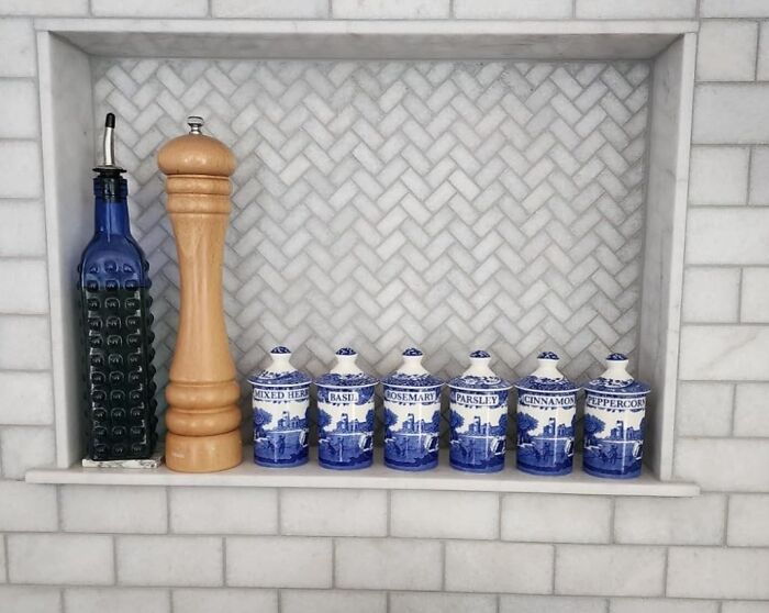 Blue and white herb jars with wooden pepper grinder and olive oil bottle on marble shelf, unique gifts for the person who has everything.