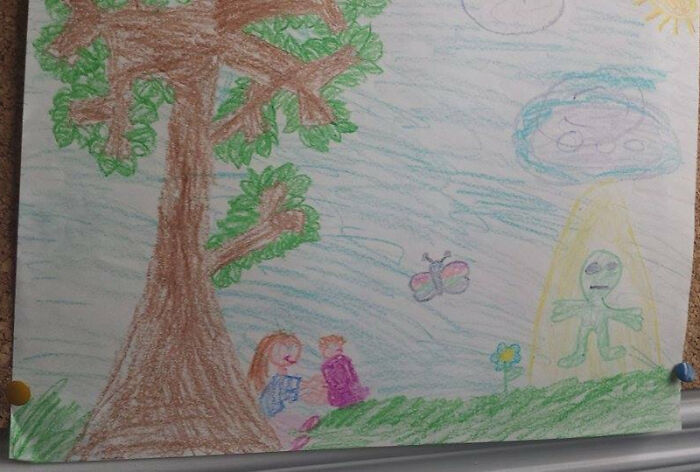 Child’s drawing of a funny portrait featuring a large tree, two kids, a butterfly, and a green alien in a light beam outdoors.