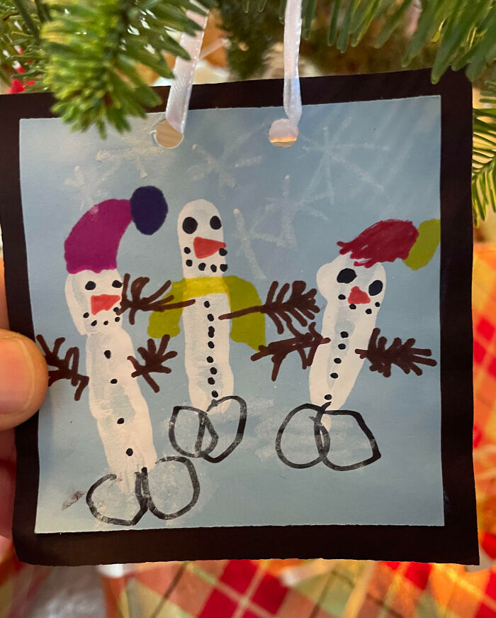 Child's funny drawing of snowmen with colorful hats and buttons hanging as a portrait in a festive setting.