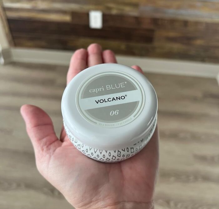 Hand holding a capri BLUE Volcano scented candle, a popular host gift for saying thank you beyond a bottle of Merlot.