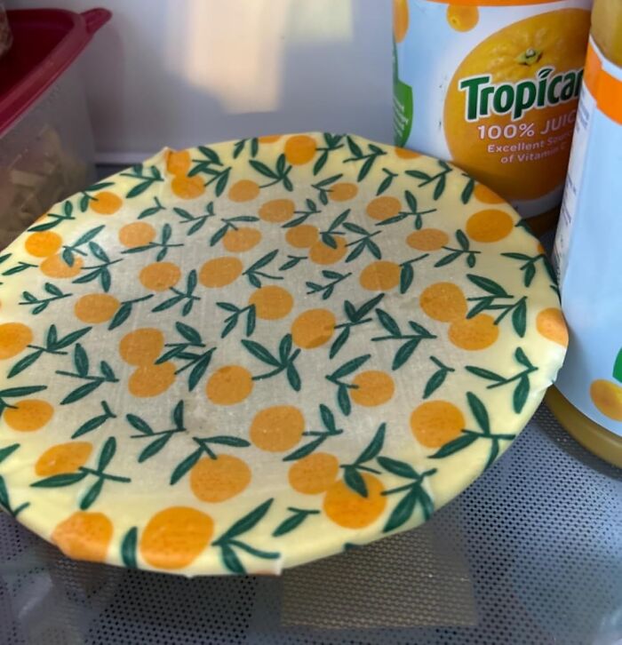 Bee's wrap with orange fruit pattern covering a bowl, showcasing eco-friendly host gifts for food lovers.