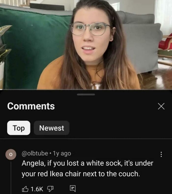 Young woman in glasses reacting to a funny comment about a lost sock under a red Ikea chair, capturing hilarious posts laughter.