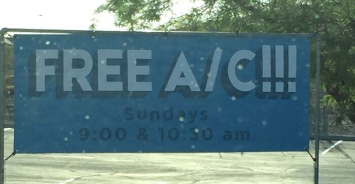 Blue church sign outdoors advertising free A/C and Sunday service times, one of the funny church signs with jokes collection.