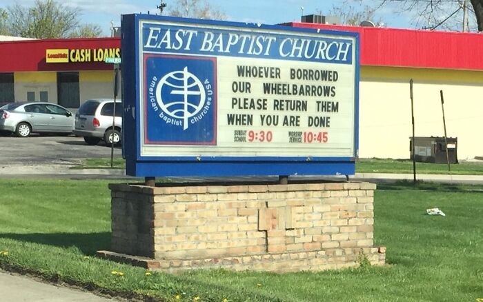 Church sign at East Baptist Church with a humorous message about returning borrowed wheelbarrows on a sunny day.