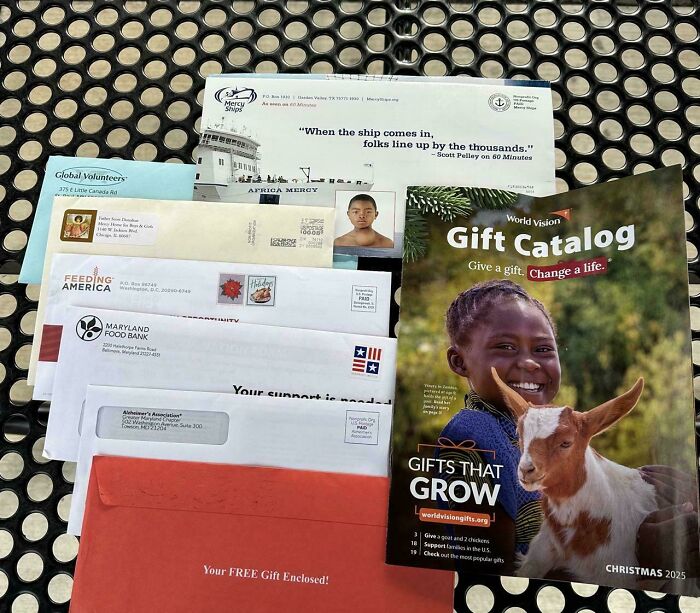 Pile of charity envelopes and a World Vision gift catalog on a metal table, unwanted mail that annoys next-level jerks