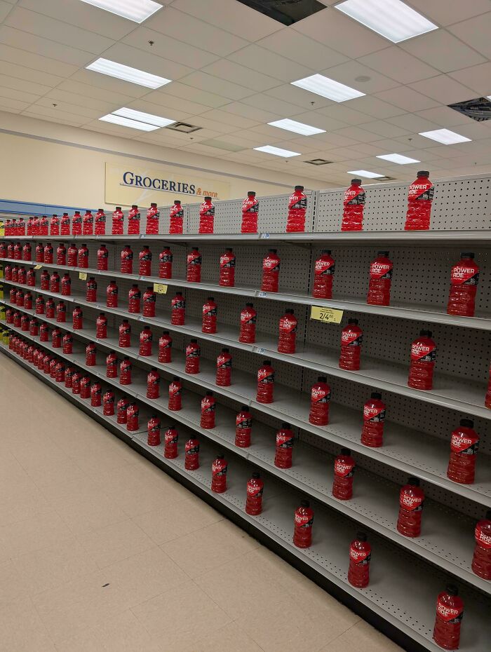 Store shelves with evenly spaced red Powerade bottles create a strange liminal space resembling backrooms atmosphere.