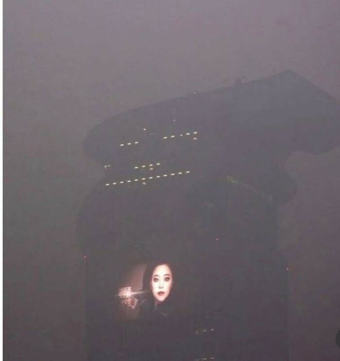Faint image of a building with a screen showing a face, surrounded by fog creating a creepy liminal space atmosphere.