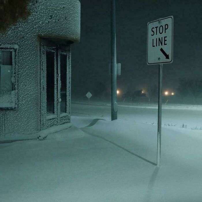 Snow-covered desolate street corner with stop line sign, capturing eerie liminal spaces that resemble the backrooms atmosphere.