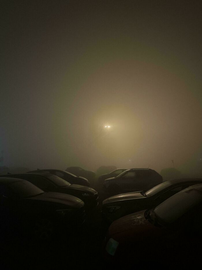Foggy parking lot at night with dim light, creating a creepy liminal space that resembles the backrooms atmosphere.