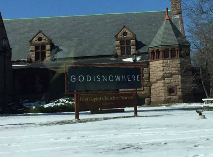 Church sign with a clever joke reading GODISNOWHERE outside a stone building in a snowy setting, church signs with jokes.