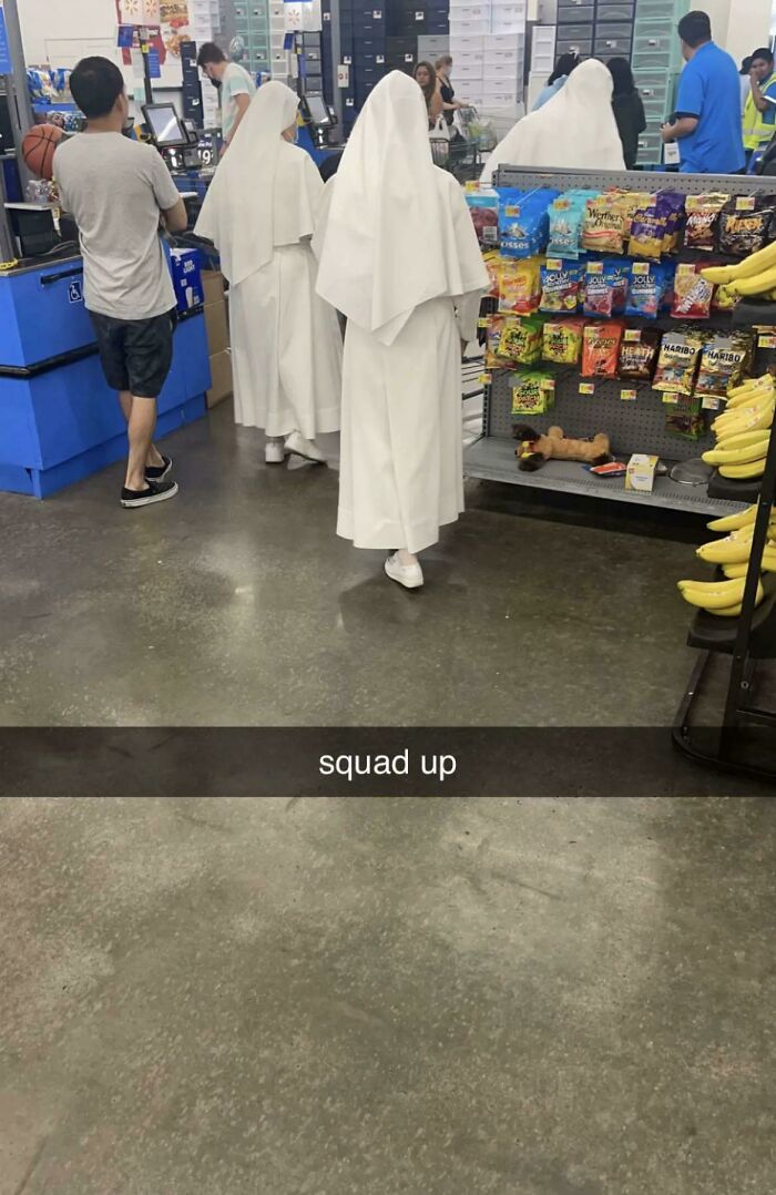 Three women dressed as nuns walking inside Walmart near checkout and snack aisle with bananas on display.