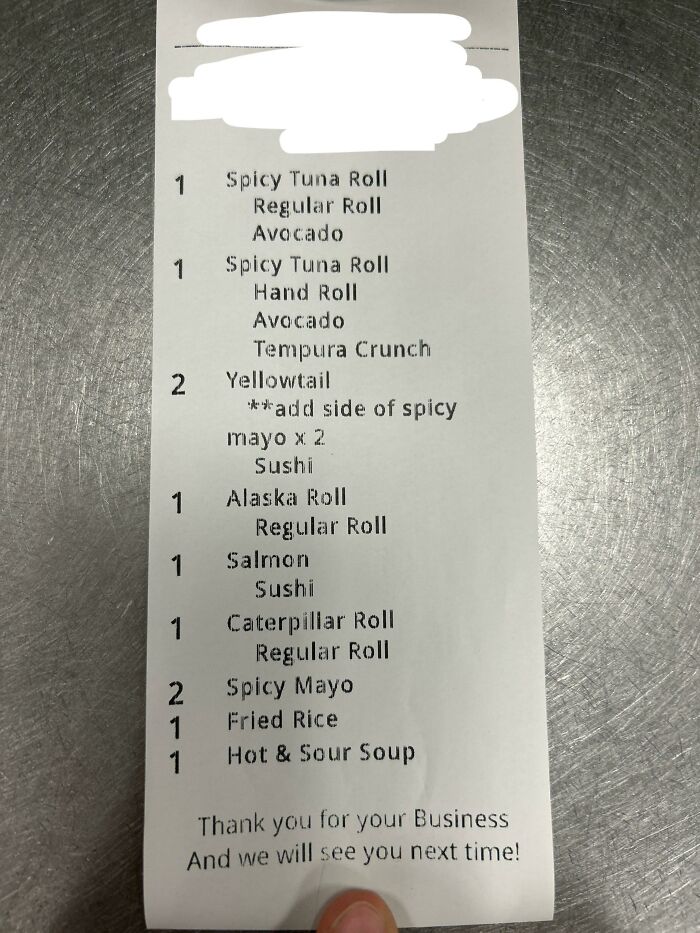 Sushi order receipt on metal counter with finger visible and scribbled top, next-level jerks