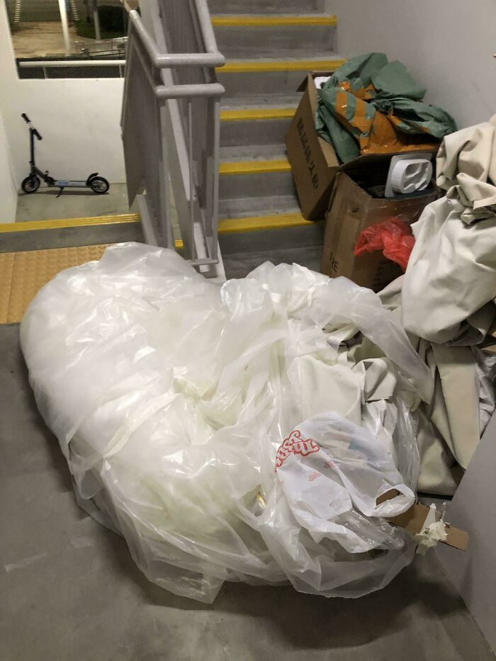 next-level jerks leaving large plastic-wrapped trash and cardboard blocking apartment stairwell landing