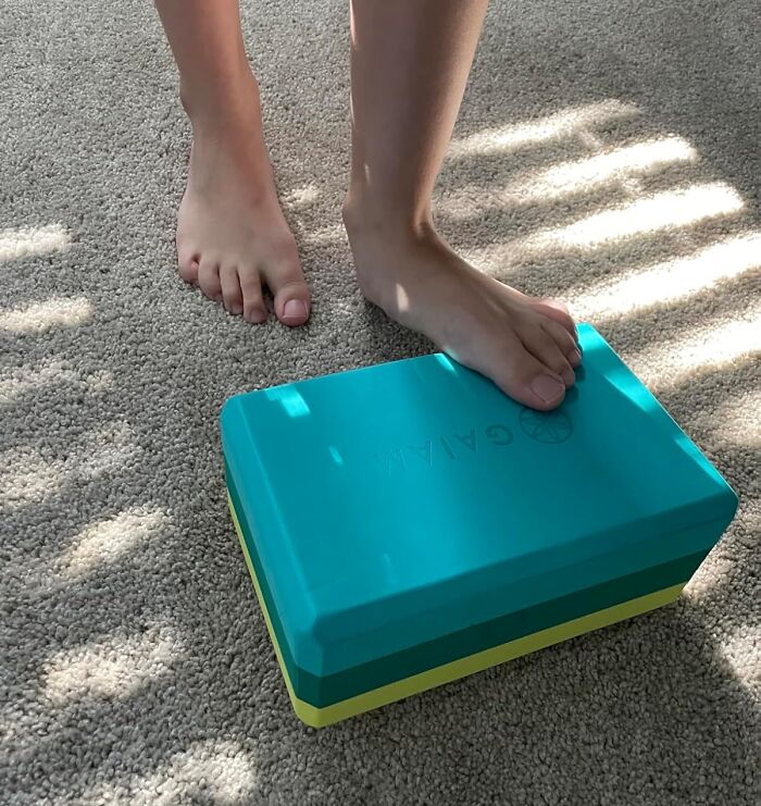 Feet balancing on a yoga block on carpet, demonstrating apartment friendly fitness exercise for smashing fitness goals.