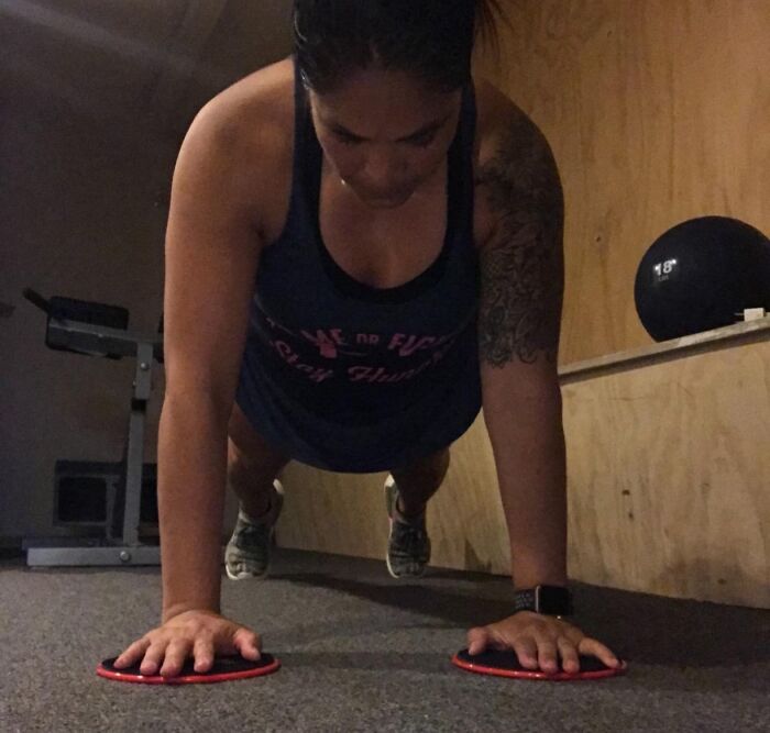 Woman doing push-up slides indoors, demonstrating apartment friendly fitness exercises to smash fitness goals.
