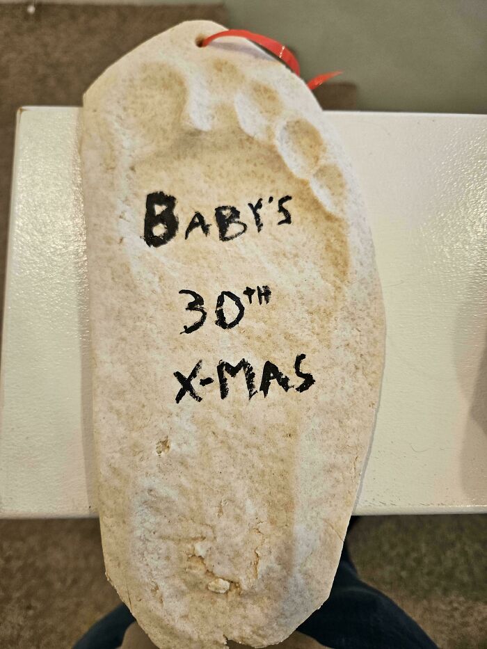 Funny pictures 2025: plaster baby footprint ornament labeled Babys 30th X-Mas on tabletop