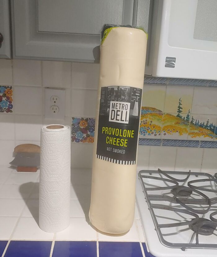 Unusually large provolone cheese next to a paper towel roll, one of the most bizarre Christmas gifts received.