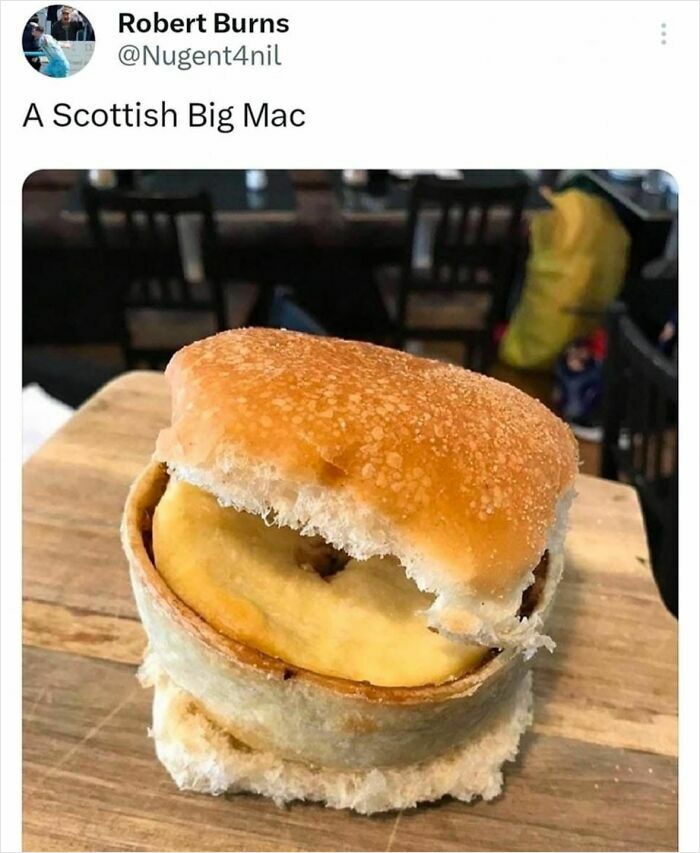 Funny food meme showing a Scottish Big Mac with unusual ingredients in a sandwich bun on a wooden table.