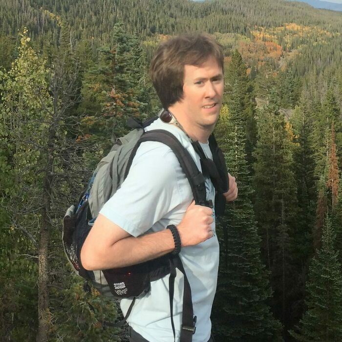 Man hiking with backpack in forest, enjoying outdoor adventure that shows life is more fun with siblings.
