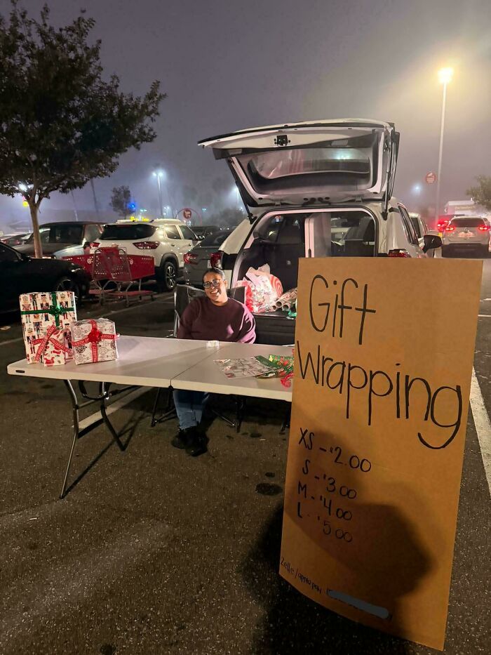 Person offering gift wrapping services at a parking lot setup with a large sign listing prices, seen in interesting new pics.