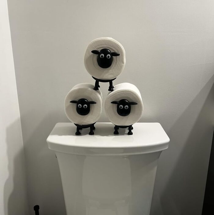 Three toilet paper rolls with black sheep faces stacked on a white toilet tank, a quirky best sellers product in 2025.